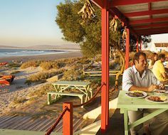 Guests enjoy West Coast seafood on the patio of the Voorstrandt Restaurant, located on Paternoster's typically West Coast beach.