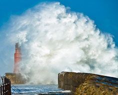 A storm wave breaks over one of the piers that guard the Kowie River Mouth at Port Alfred on South Africa's Sunshine Coast.