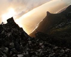 A fisheye-lense capture from atop Table Mountain showing the top Cable Way station, a cable car, Lions Head, the Cape Town city bowl and Table Bay.