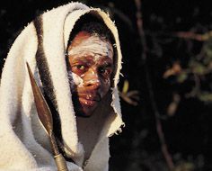 A Xhosa intiate with white clay on his face, a traditional blanket and spear.